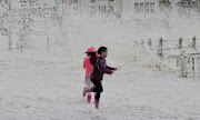 Two girls, Liv (right) and Eve Dorrington, enjoy playing in the ocean foam at the Sea Point Promenade in Cape Town on July 13 2020. 