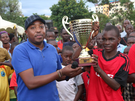 SKF Kenya and East Africa region Managing Director Harris Kariuki handing over trophy to the captain of the Kisumu Youth Olympic soccer team Ben Onysango. The Team won the under 15 soccer title and has since landed an invitation to play in the Gothia Cup in Sweden. /Sonu Tanu