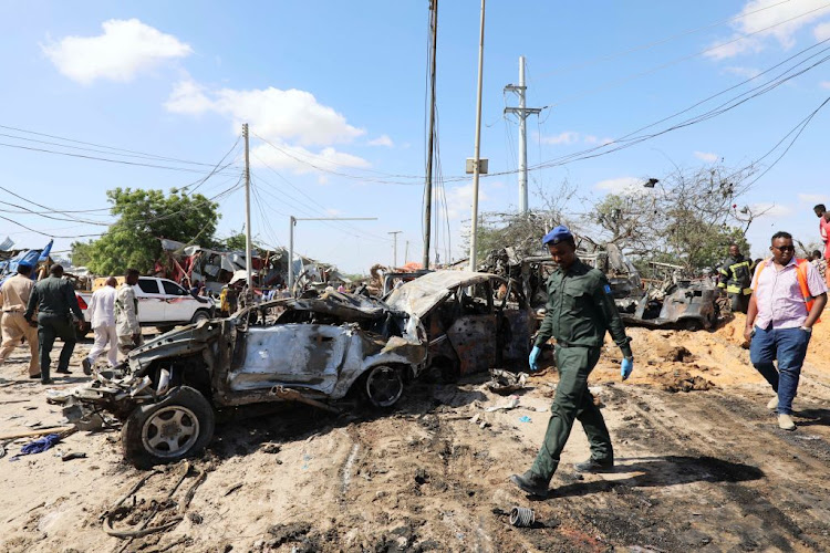 A Somali police officer walks past the scene of a car bomb explosion at a checkpoint in Mogadishu, Somalia, on December 28 2019. The US military responded to the bombing with three air strikes.