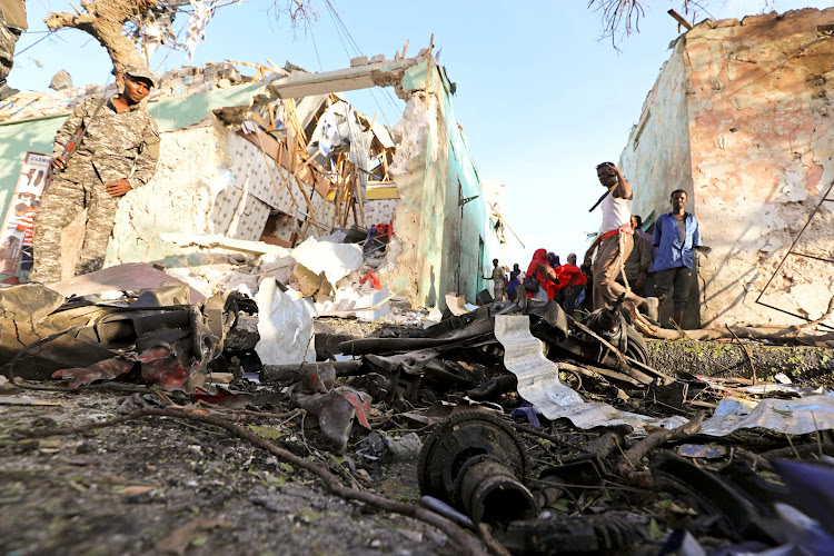 Somali security forces and civilians assess the damage at the scene of an explosion outside Weheliye Hotel in Maka al Mukarama street in Mogadishu, Somalia March 22, 2018.