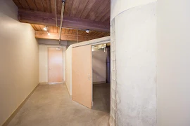 Entryway area with exterior wood door, next to bedroom with sliding wood door