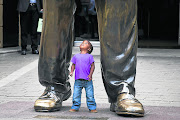 Otlile Monama, three,  stands under a  statue  of former  president Nelson  Mandela , in Nelson  Mandela  Square. File photo.