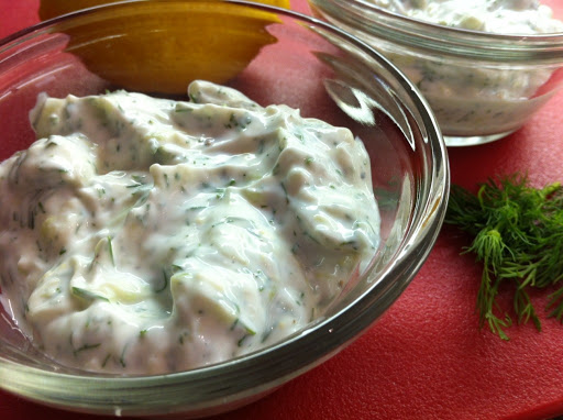 Sauce in two glass bowls sitting on a red table mat with parsley and a lemon.