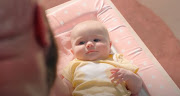 A scene from the ad in which a father changes his baby daughter's nappy.