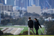 People wearing face masks walk through a park in Melbourne as the city operates under lockdown in response to an outbreak of Covid-19 in Australia, on September 2 2020. 