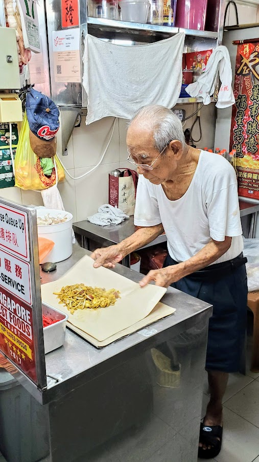 Guide to visiting Hawker Centers in Singapore - Tiong Bahru Char Kway Teow (Stall #02-11) to meet Mr. Tay Soo Nam, who started frying noodles at the age of 24 and although isn't doing the cooking now (he leaves it up to his daughter and husband) is still manning the hawker stall at 90 years old. The only dish to get here is the Char Kway Teow with chinese sausage, fishcake, cockles and beansprouts.