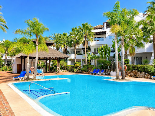 Buy this luxury property in Marbella (Spain) - Outdoor swimming pool with palm trees and building