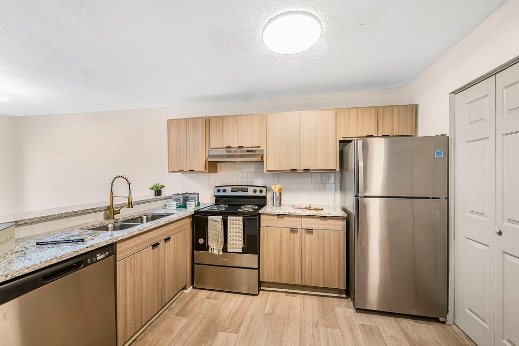 Kitchen view with white cabinets, stainless steel appliances, view to dining room with sliding glass door