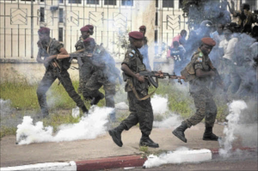 CAUGHT IN CROSSFIRE: Members of the presidential guard are caught in teargas fired by police at a crowd of opposition supporters outside N'Djili Airport in the DRC capital Kinshasa . Police blocked President Joseph Kabila's main rival at an airport in the city on Saturday to stop him staging an election rally after at least two people were killed in violence across the country's capital city. Photo: REUTERS