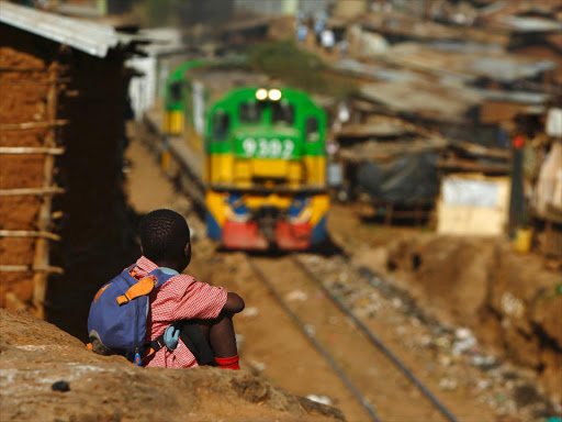 A child watches a train passing through the Kibera slum in this file photo taken February 26, 2015. /REUTERS