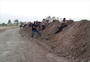 Backing government forces, take a position behind a berm as they fire at Islamic State (IS)  group positions. Picture Credit: AFP