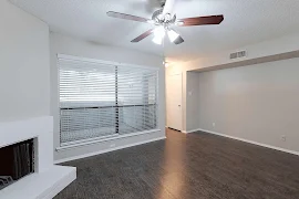 Living room with large windows, dark wood floors, white brick fireplace, ceiling fan