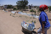 Shela Molomo from Juju Valley informal  settlement in Seshego pushing a wheelbarrow carrying water containers after casting her vote earlier today.