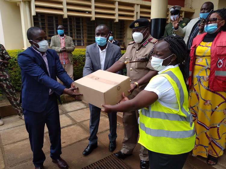 Nyamira County Commissioner Amos Mariba (in uniform) receives hand sanitizers donated by Kenya Pipeline Company.