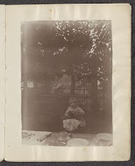 Vrouw en een kind zittend aan een houten tafel in een tuin