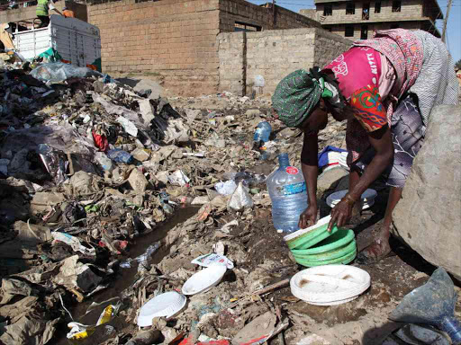 Marita Saie, 59, washes plastic plates which she has collected from the vast mountain of garbage in Dandora slum on the outskirts of Nairobi, January 23, 2018. /Thomson Reuters Foundation/Nita Bhalla