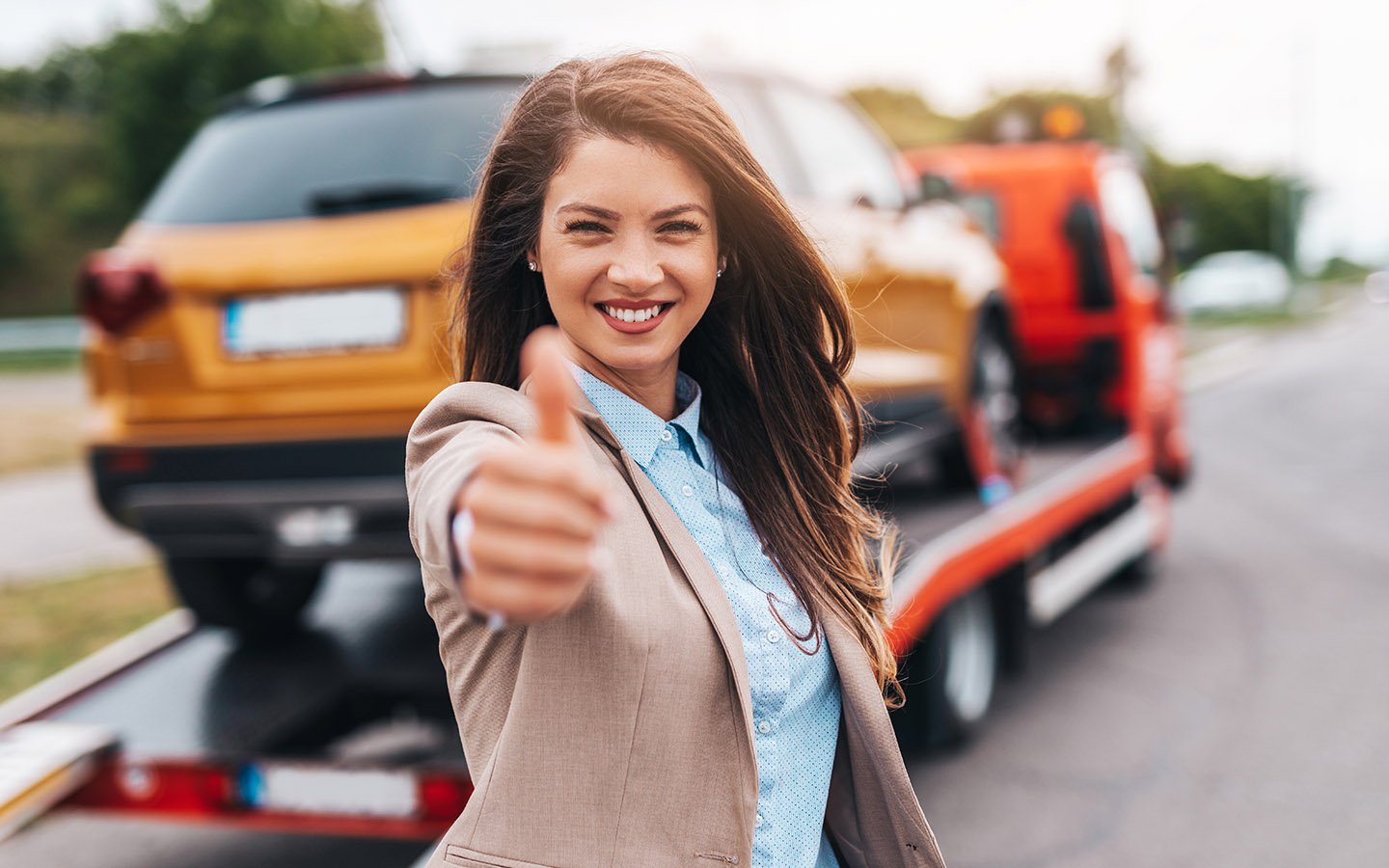 woman giving thumbsup after her vehicles is handled by roadside assistance insurance program