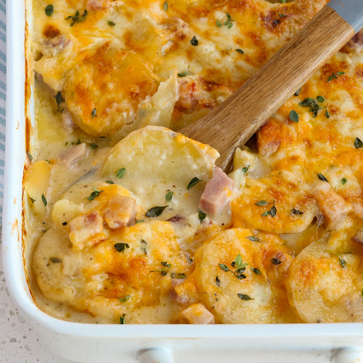 Scalloped Potatoes and Ham Casserole is sliced Yukon gold potatoes and smoked ham in a delicious creamy lightly seasoned white sauce all topped with sharp cheddar and Monterey Jack Cheese.