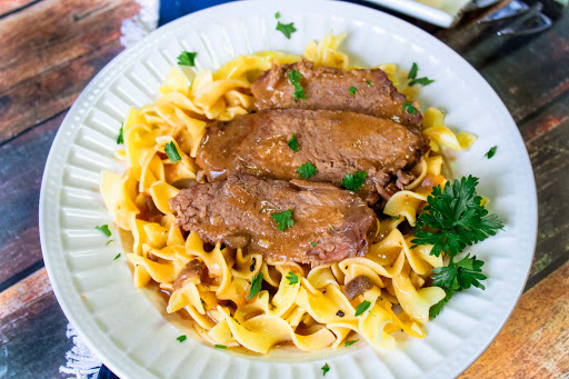 Slices of Crock Pot Roast With Gravy over noodles.