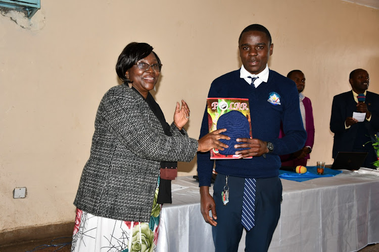 Curriculum reforms and implementation PS Fatma Chege handing a book and marvin to a student at GOA High School in Nyandarua county on Saturday, September 10.