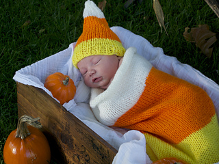 sleeping baby wearing candy corn-themed sleep sack with matching hat