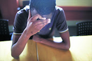 A depressed man sitting next to a table with his head in his hands. File photo.