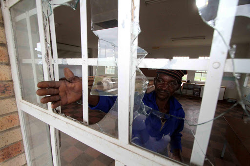 DAMAGED: Caretaker Phumzile Njengele in front of a block of classrooms at Bantini Junior Secondary School in Ngqeleni where at least 15 windows were damaged as a crowd of people who had been locked outside the venue during an ANC branch annual general meeting threw stones causing damage to the structure on Sunday evening Picutre: LULAMILE FENI