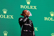 Third placed Lewis Hamilton wipes his face on the podium during the F1 Grand Prix of Hungary at Hungaroring on August 01, 2021 in Budapest, Hungary.