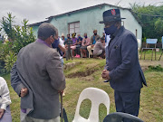 Bhekithemba Khumalo, whose brother Christopher was shot dead on Saturday along with five other family members, is seen with police minister Bheki Cele at the family home.