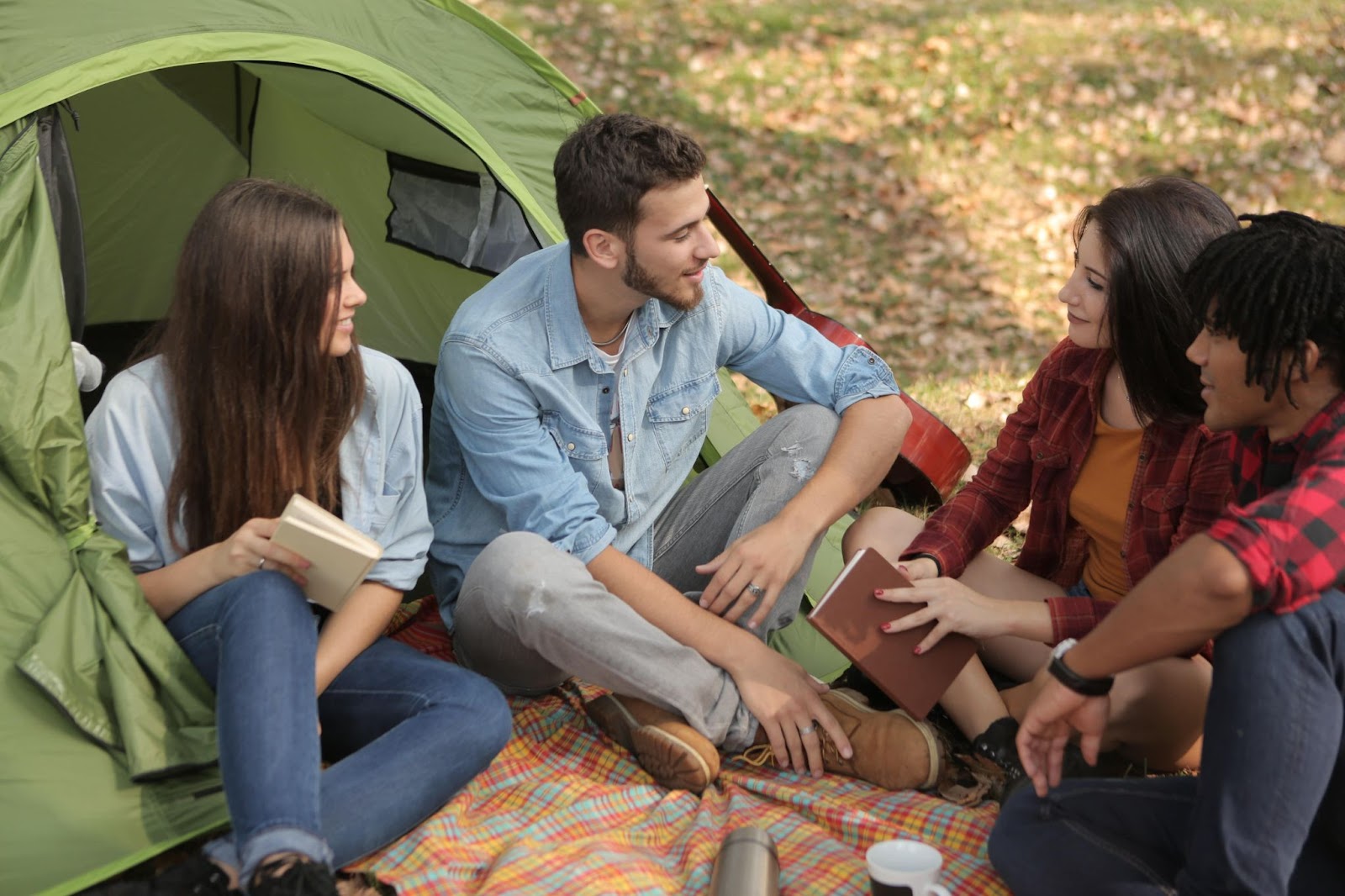 A group of people talking to each other outside a camping tent.