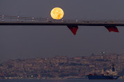 Cars drive across the July 15 Martyrs Bridge (Bosphorus Bridge) as the rare Super Blue Moon sets behind on August 31, 2023 in Istanbul, Turkey. The rare supermoon is an occurrence which won't happen again until 2037. The term 