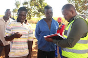 A department of employment and labour compliance inspector interviews workers.