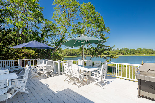 deck with tables, chairs, and lake view in this luxury property for sale in Shelter Island ($3,795,000)