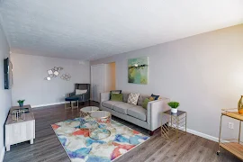 Furnished model living room with wood-inspired and a gray couch with decorative gold accents