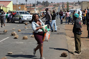 Residents of Jabavu, Soweto, loot a foreign-owned spaza shop on August 29, 2018, after Banele Qhayiso was allegedly shot dead by one of the shop owners.