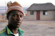 Esigodlweni resident Dumisani Ndlovu  stands next to Mongezi Mkhize's desecrated grave.