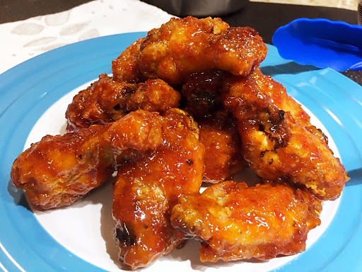 A plate of chicken wings tossed in a red sauce