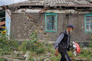 Local resident Vladimir Odarchenko, 70, carries belongings past his house damaged during Ukraine-Russia conflict in the town of Popasna in the Luhansk region, Ukraine, on July 14 2022. 