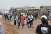 Parents are seen walking their children to school on January 12 2022 at Setlabotjha Primary School in Sebokeng, Gauteng.