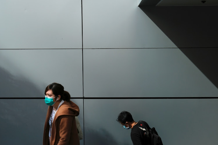 People wear protective masks as they walk outside a shopping mall, following the outbreak of the new coronavirus in Hong Kong, China February 21, 2020.