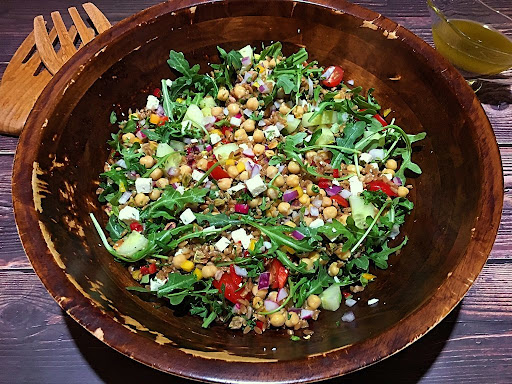 A tasty and gorgeous salad with farro, arugula, chickpeas, cucumber, feta cheese, cherry tomatoes, mixed bell pepper, red onions, radishes, pistachios, parsley and mint.