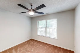 Carpeted bedroom with two windows, a ceiling fan, and neutral walls with white trim