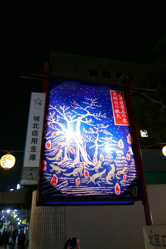 There is a famous piece of art by Utagawa Hiroshige during the 1797–1858 Edo period depicting this event showing the foxes (kitsune) gathering at a tree on New Year's Eve to pay homage at the Ōji Inari shrine, the headquarters of the Inari cult that centers on the god of the rice field, for whom the fox serves as messenger. On the way to Ōji, the foxes have set a number of kitsunebi (foxfires), which farmers count to predict the upcoming rice harvest. You may see versions of the art around the area like we did.