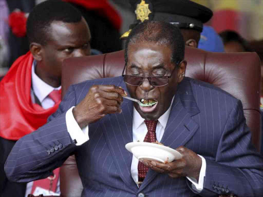 Zimbabwe's then-President Robert Mugabe eats cake at his 92nd birthday celebration in Masvingo, on February 27, 2016. /REUTERS