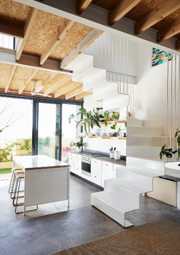 The front door of the Longs’ home opens into a living and dining area that leads to a courtyard on the far side, and includes the compact staircase, elegantly fashioned from steel, that leads up to the floors above. The kitchen island doubles as a dining table, and there is plenty of storage to facilitate a clean-lined look. The open shelves keep regularly used pieces at arm’s reach, as well as creating a zone for lively display that includes plenty of indoor greenery – and Patsy the cat, of course. All the cabinetry and shelving was designed and built by David Long.