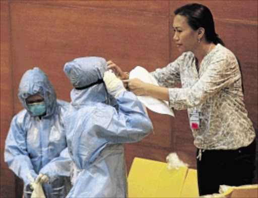 SAFETY: A Philippine health worker assists a colleague with a protective suit and equipment during the One Nation, One Direction for Ebola Prevention training at the Research Institute for Tropical Medicine in Alabang, south of Manila, yesterday PHOTO: Romeo Ranoco/REUTERS