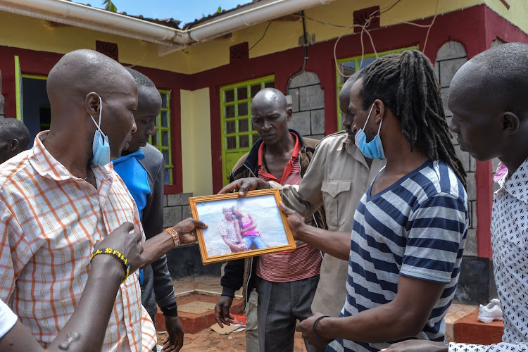 Family members of Agnes Tirop, Kenyan distance runner who was found dead with stab wounds at home, look at her portrait with her husband before burning it at the crime scene of Tirop's home in Iten, Kenya, on October 18, 2021. - Tirop, 25,†was a fast-rising athlete -- a double world 10,000m bronze medallist and 2015 world cross county champion who also finished fourth in the 5,000m at the Tokyo Olympics this year. (Photo by Casmir ODUOR / AFP)