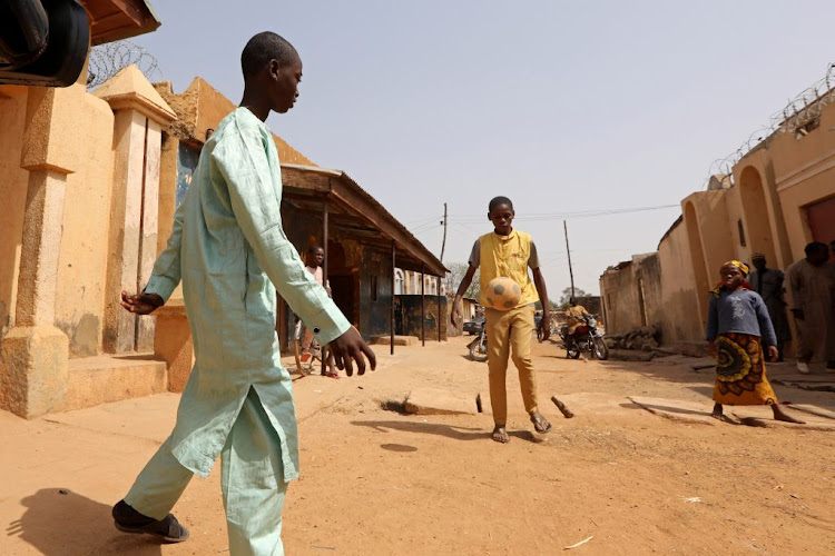 Annas Shuaibu, a student, plays football with his friend in Kankara, in Nigeria, recently. The country's government says it will claw into unclaimed dividends to fund deficit.