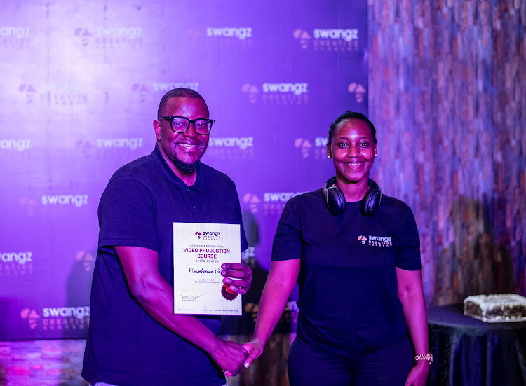 Benon Mugumbya Head of production at Swangz avenue (left) awarding one of teh graduates