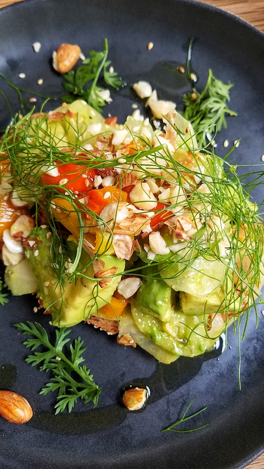 Green Tomatoes (vegan) featuring green tomato salad, marinated avocado, sprouted almonds, blackened peppers, herbs, grain sourdough toast from Brunch at Proud Mary Coffee in Portland, at 2012 NE Alberta St